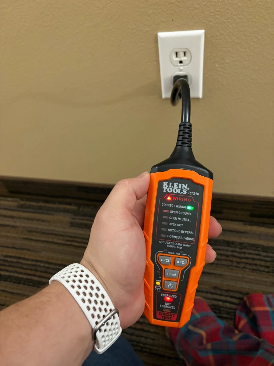 Electrician testing a hallway receptacle after troubleshooting in a Burnsville, MN HOA building.